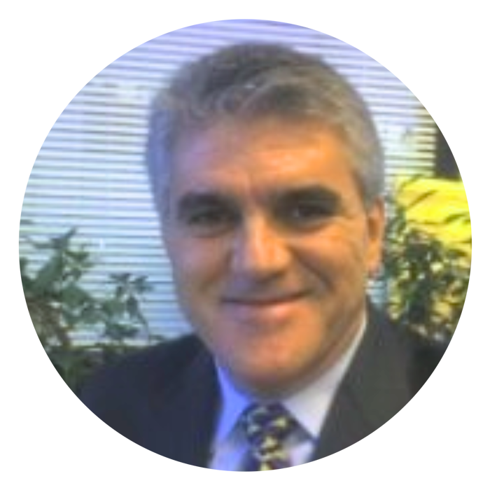 Man with pepper hair in suit and tie smiling 