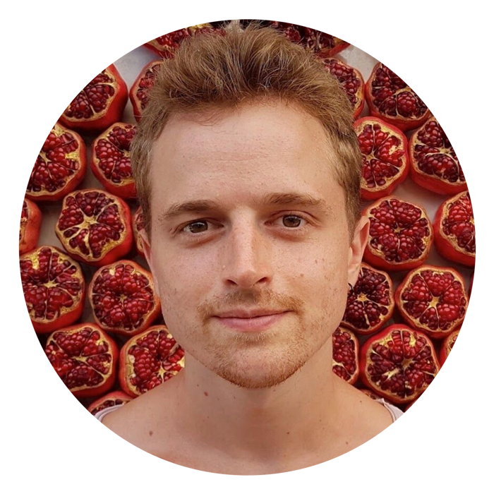 Man with strawberry blonde hair smiling in front of pomegranates