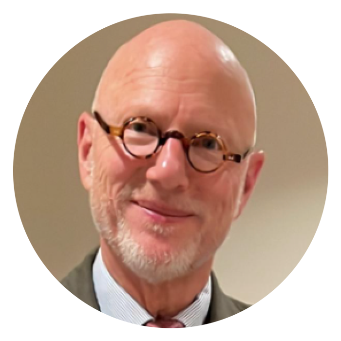 Bald man with white goatee and small round glasses smiling