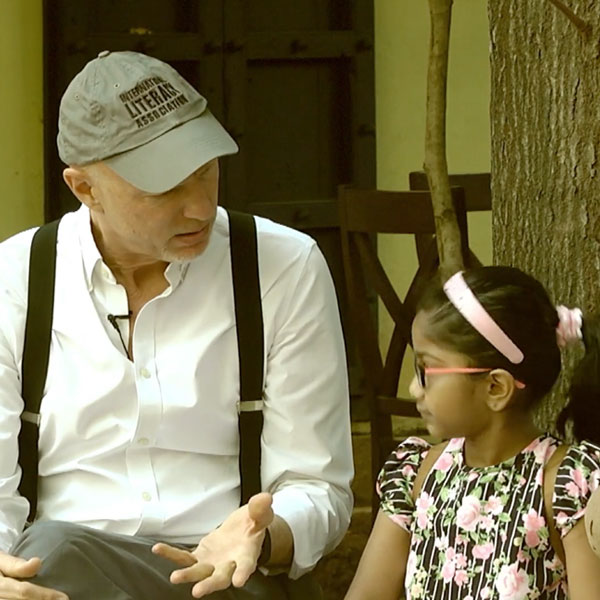 Man in ballcap speaking to a young girl with a floral dress